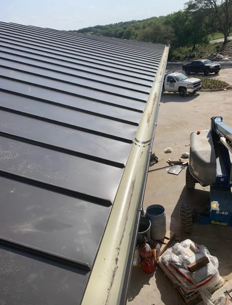 Standing seam panel and gutter detail on a metal roofing jobsite in Needham